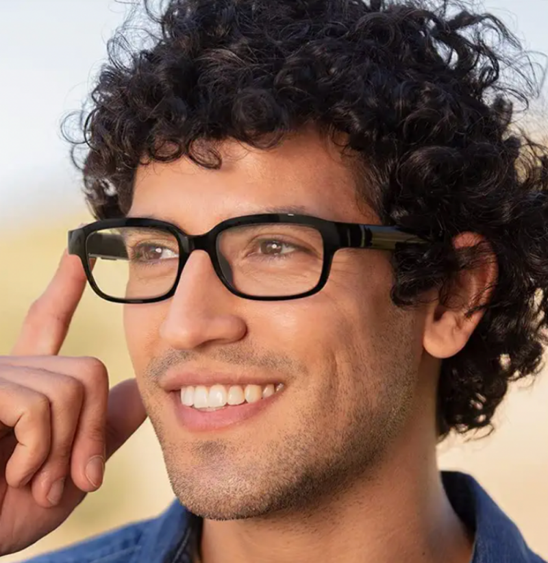   Um homem de cabelos escuros usando o controle de toque em seus óculos inteligentes Amazon Echo 2nd Generation