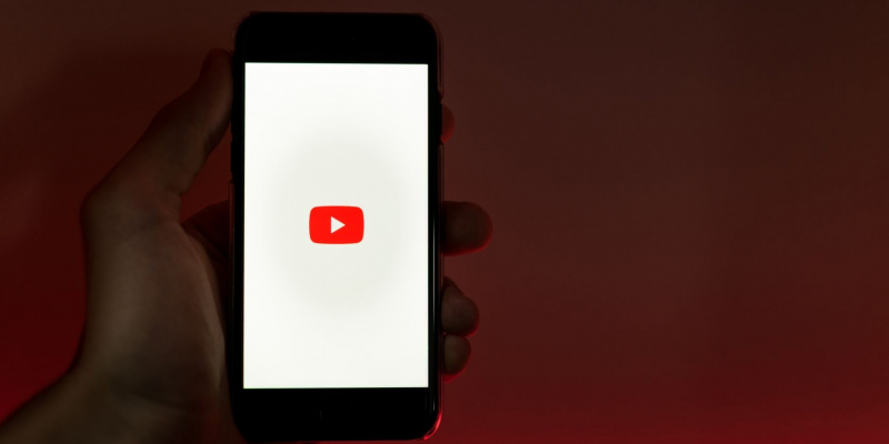   personne tenant un smartphone affichant le logo youtube