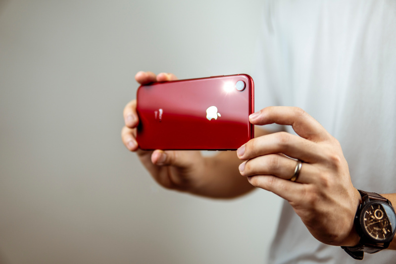   fotografija nekoga, ki se slika z rdečim iphoneom