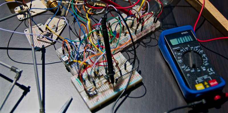   dráty, elektronika a měřič napětí ležící přes stůl