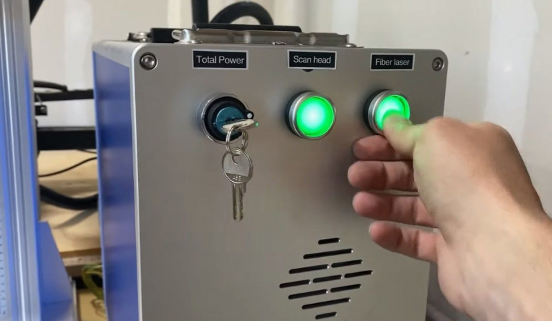   Sebuah tangan menyentuh tombol laser serat