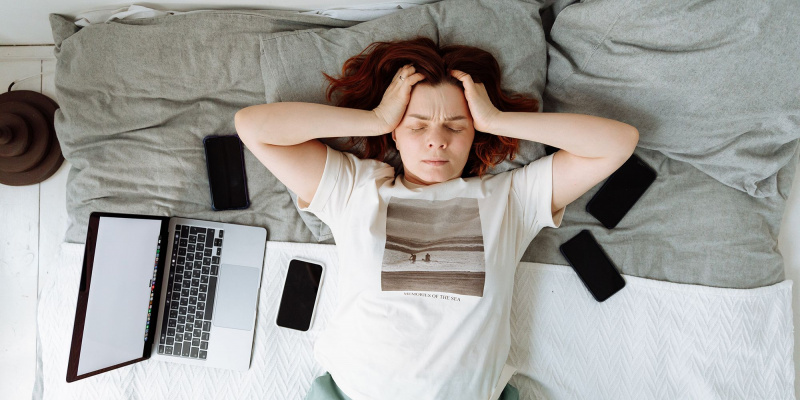   Dona estirada al llit frustrada amb l'ordinador portàtil