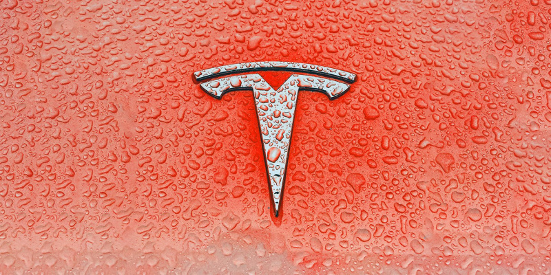   blöt Tesla-logotyp på röd bakgrund