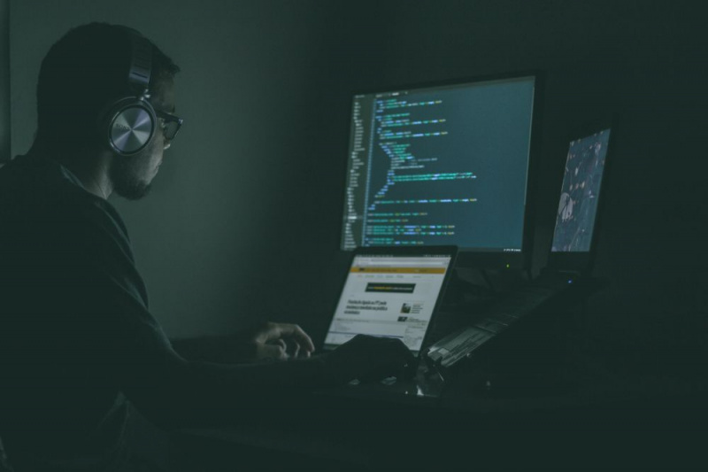  Lelaki menulis kod pada dua komputer riba dan menayangkan pada monitor