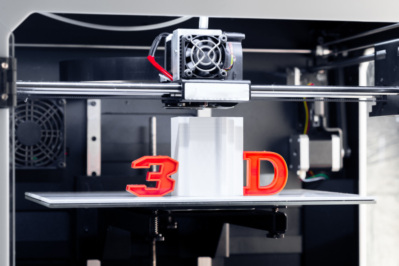   빌드 플레이트에서 3D 인쇄되는 모델의 양면에 3D 및 D 문자가 있는 작동 중인 3D 프린터
