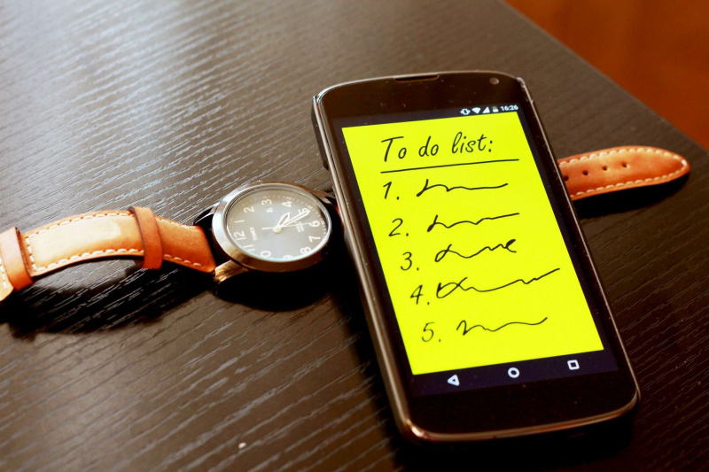   Hnedé náramkové hodinky a smartfón so zoznamom úloh